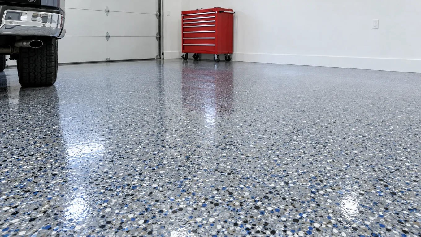 Decorative flake garage floor in gray, black, white and blue flecks with a glossy clear coat and a red tool chest