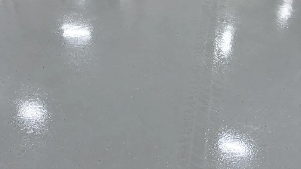 Top-down close-up of a smooth light-gray glossy epoxy garage floor