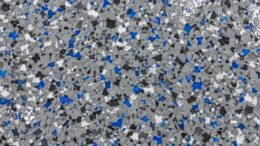 Top-down close-up of a gray, charcoal, white and blue vinyl flake garage floor